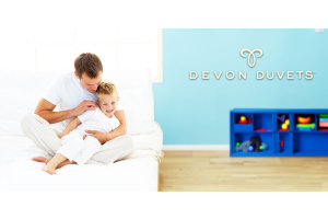 A lifestyle shot of a child and his father playing in the bedroom with Devon Duvets.
