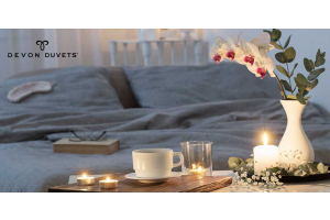 A romantic candlelit dinner setting in front of a luxuriously handcrafted Devon Duvets wool bedding, symbolising the warmth and comfort our products bring to your personal spaces.