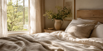 Natural bedroom with wool bedding, soft morning light and an open window looking out to trees