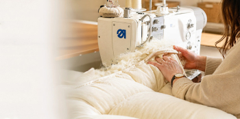 a seamstress using a sewing machine to make a wool duvet comforter.
