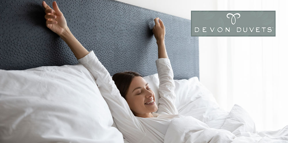 Woman stretching in bed, symbolizing a refreshing start to the day and the importance of a good morning routine.