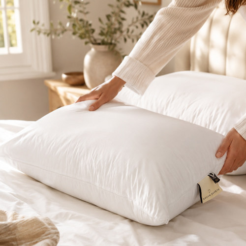 Person adjusting a Devon Duvets wool pillow on a naturally styled bed