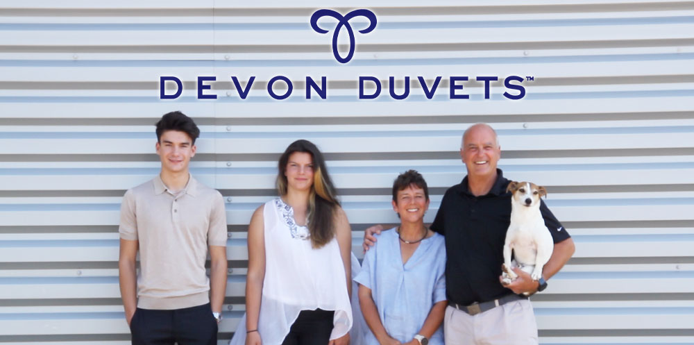 The Devon Duvets family, including founders Dick and Pauline, standing proudly in front of their workshop, embodying their commitment to handcrafted sustainability.