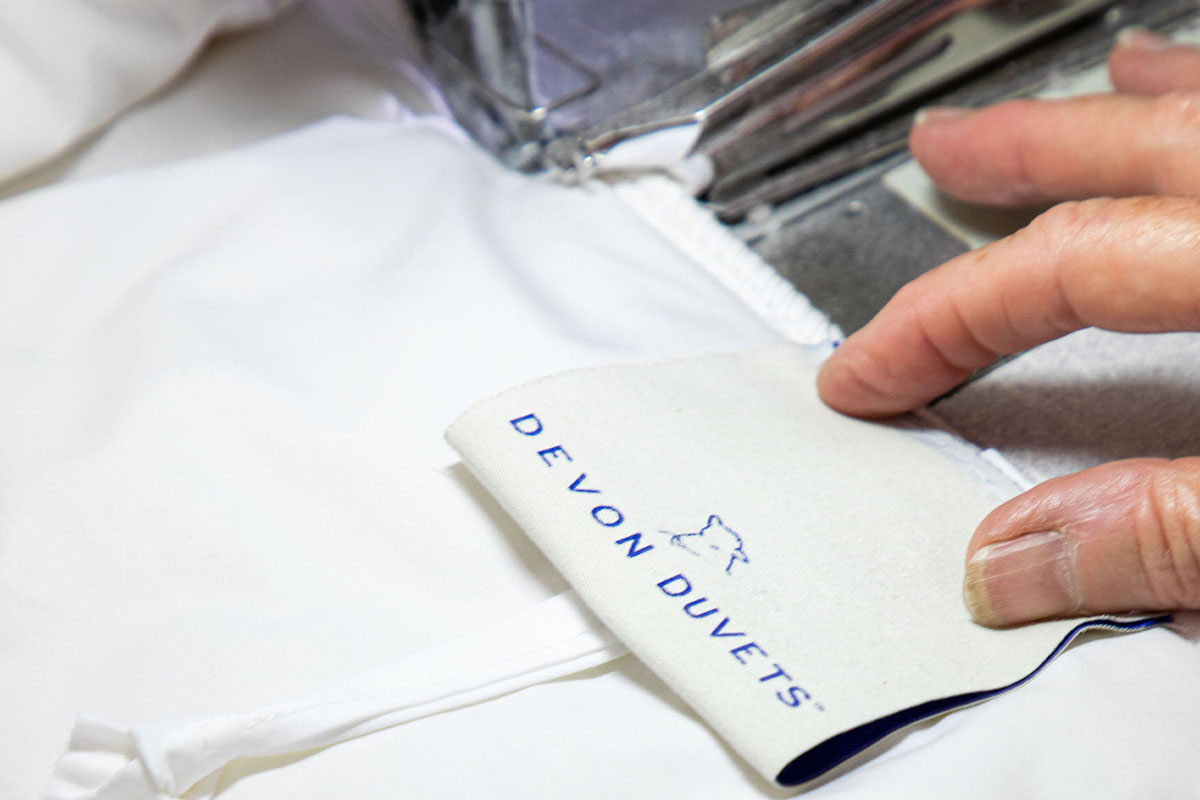 A skilled maker carefully stitching natural bedding in a Devon workshop