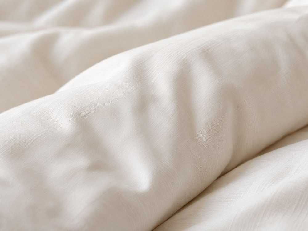 A close-up of cotton bedding fabric and its stitching.