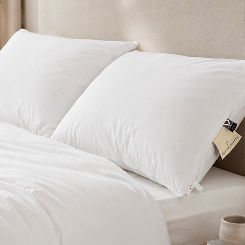 Two natural wool pillows arranged against a neutral upholstered headboard