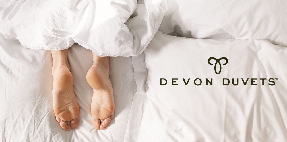 Feet comfortably resting at the bottom of a bed, conveying the calm sleep environment created by using temperature-regulating bedding to ease RLS.