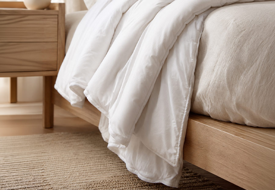 Wool duvet falling naturally over the side of a bed showing the soft drape of its cotton casing.