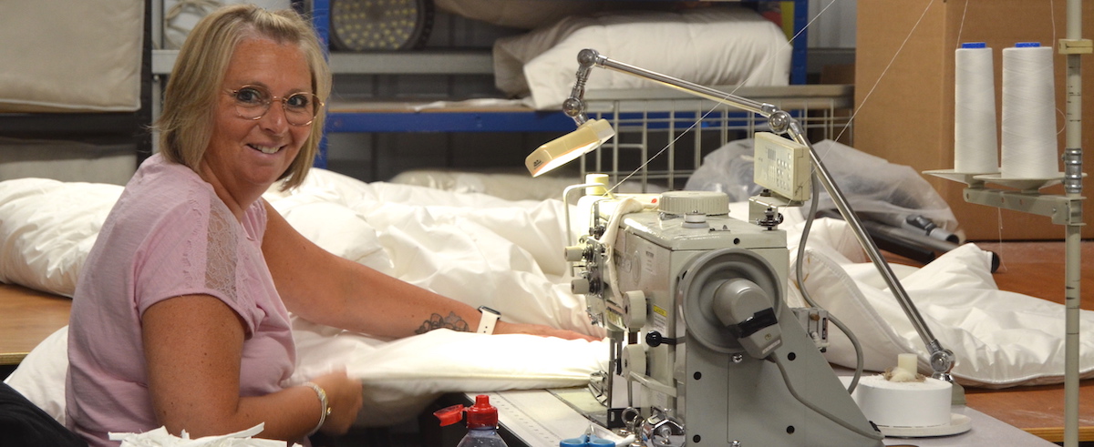 Skilled seamstress meticulously crafting quality bedding, showcasing expert craftsmanship and attention to detail.