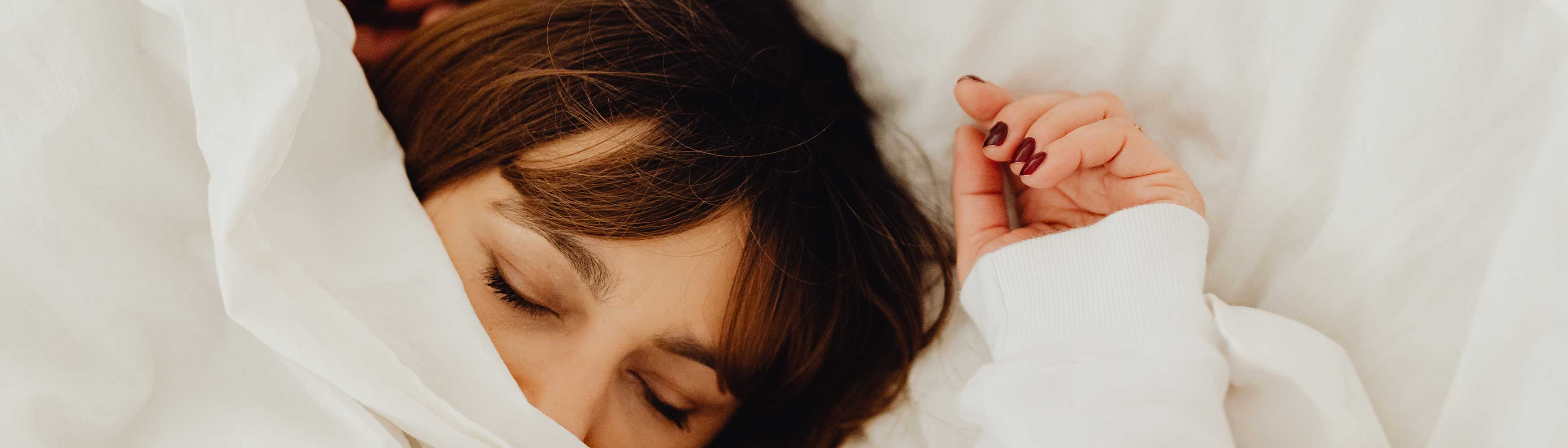 Woman snuggled up under cosy duvet for a good night's sleep