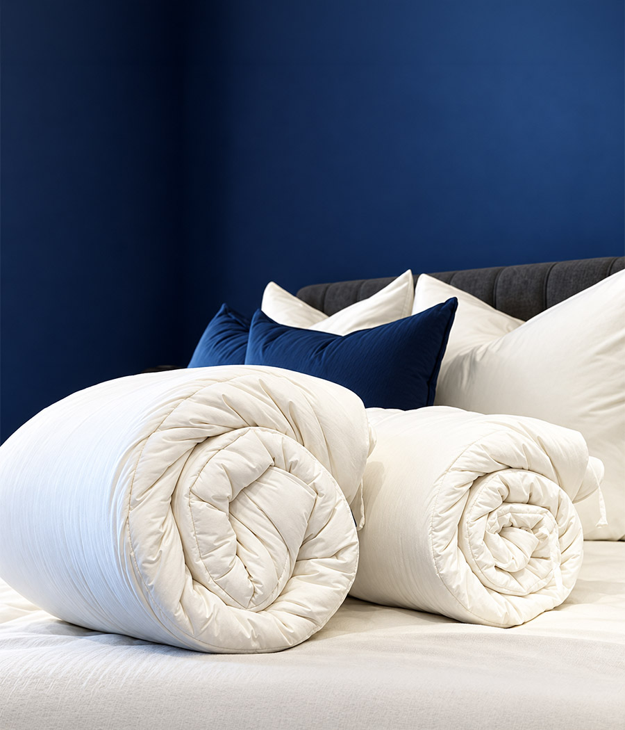 Rolled ivory duvet on a bed in a navy bedroom.
