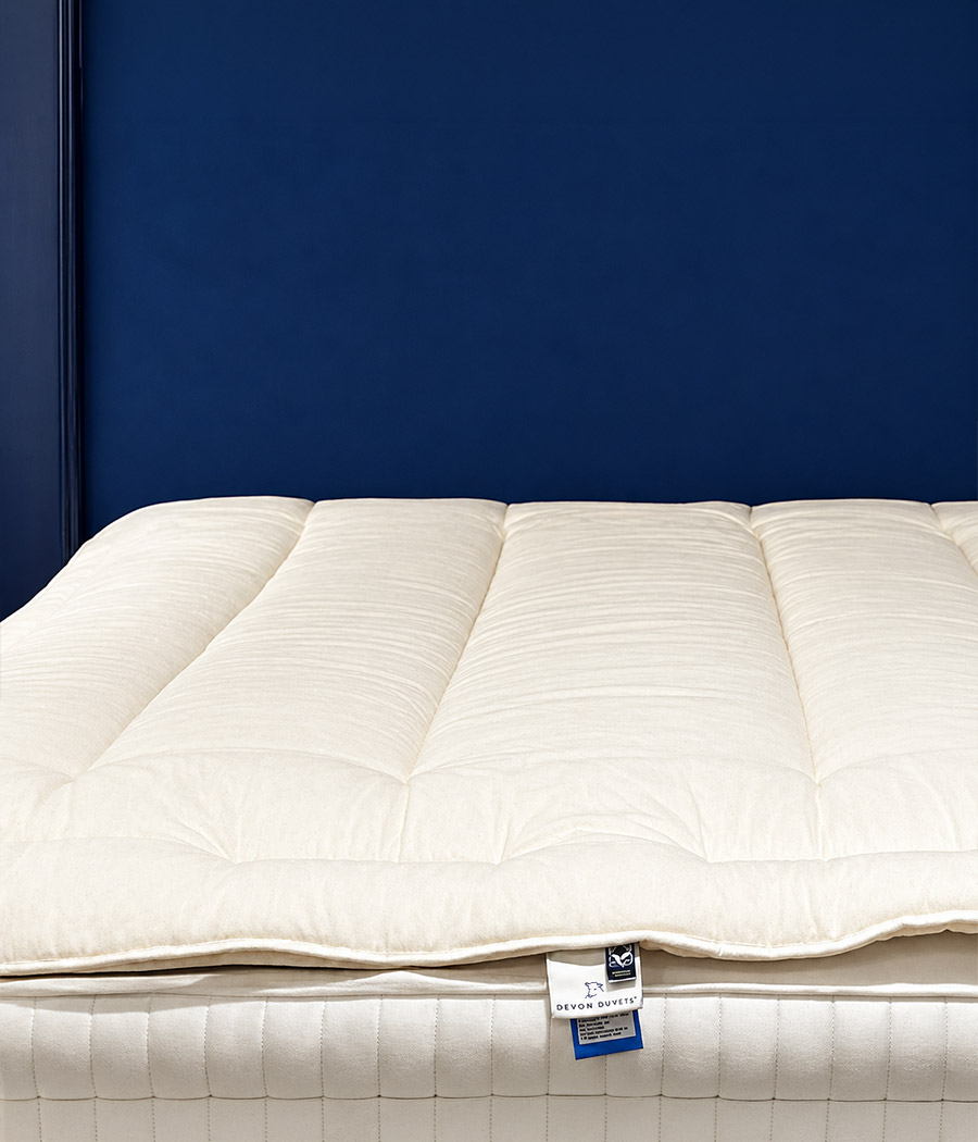 Cotton-cased wool mattress topper on an ivory mattress.