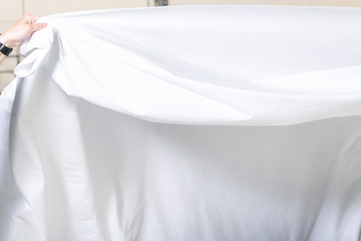 Close-up of ivory cotton bedding with soft folds and visible woven texture.
