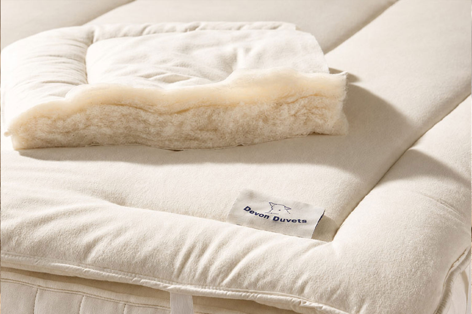 Natural wool fibres resting beside softly folded ivory cotton fabric.