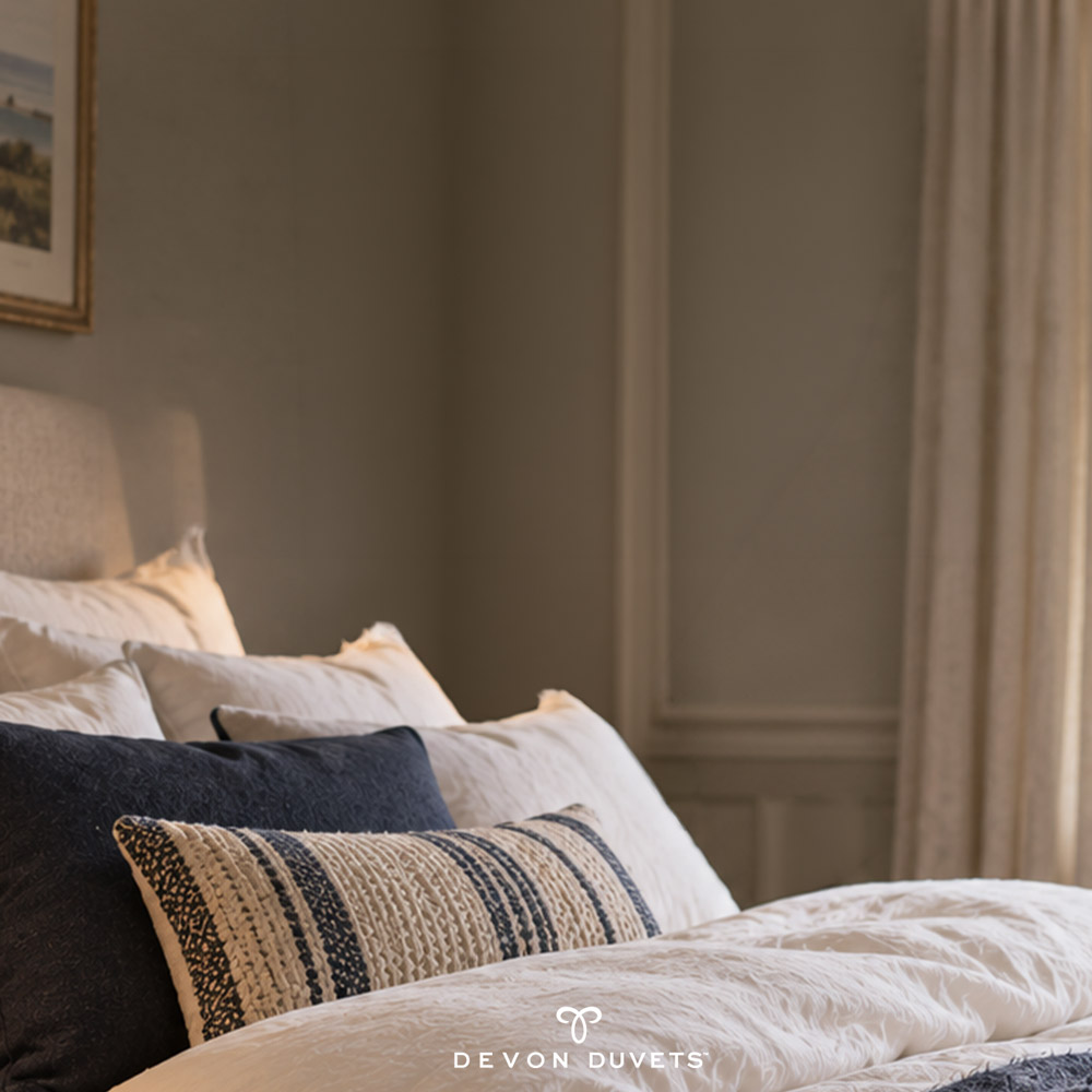 Morning light falling across white bedding and textured cushions