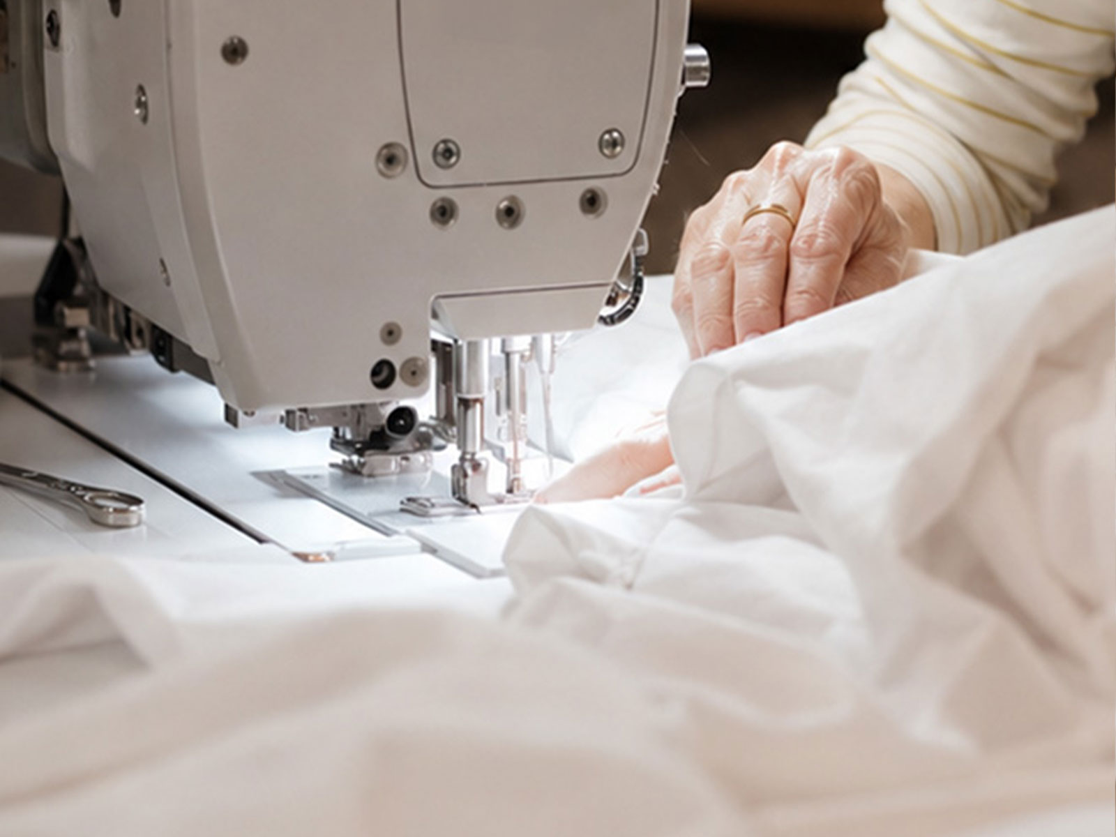 A maker working with cotton fabric and prepared wool on a bedding workshop table