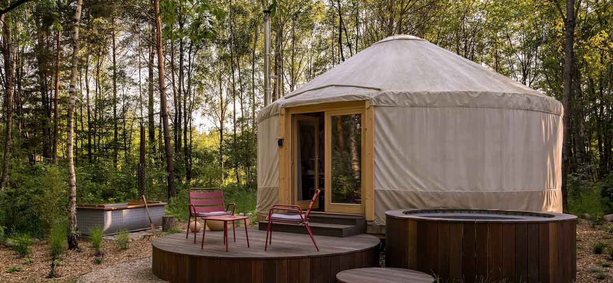 Luxury glamping yurt with a private hot tub and seating deck, nestled in a peaceful woodland setting