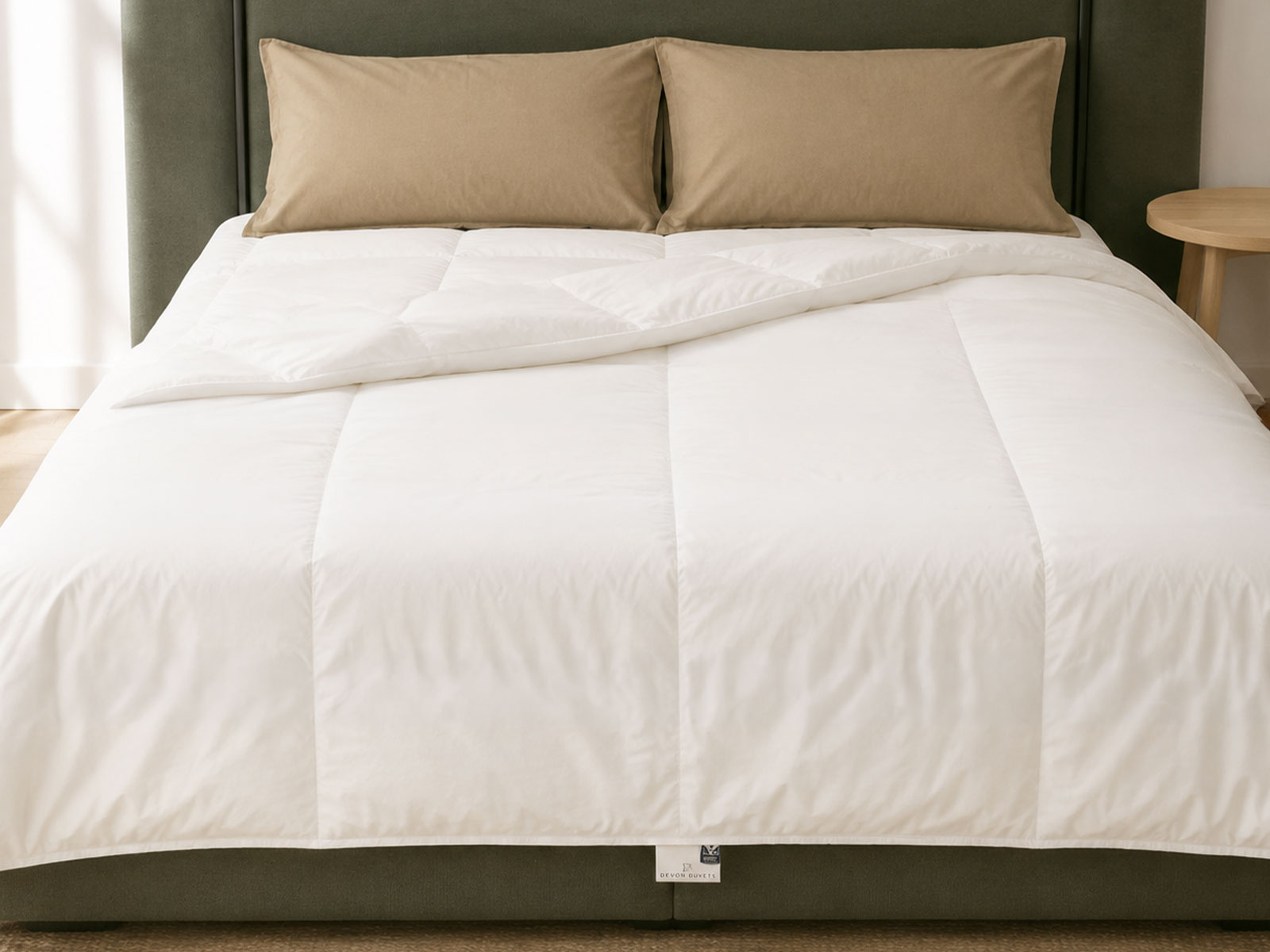 A cream cotton-covered wool duvet and pillows arranged on a bed in a calm bedroom