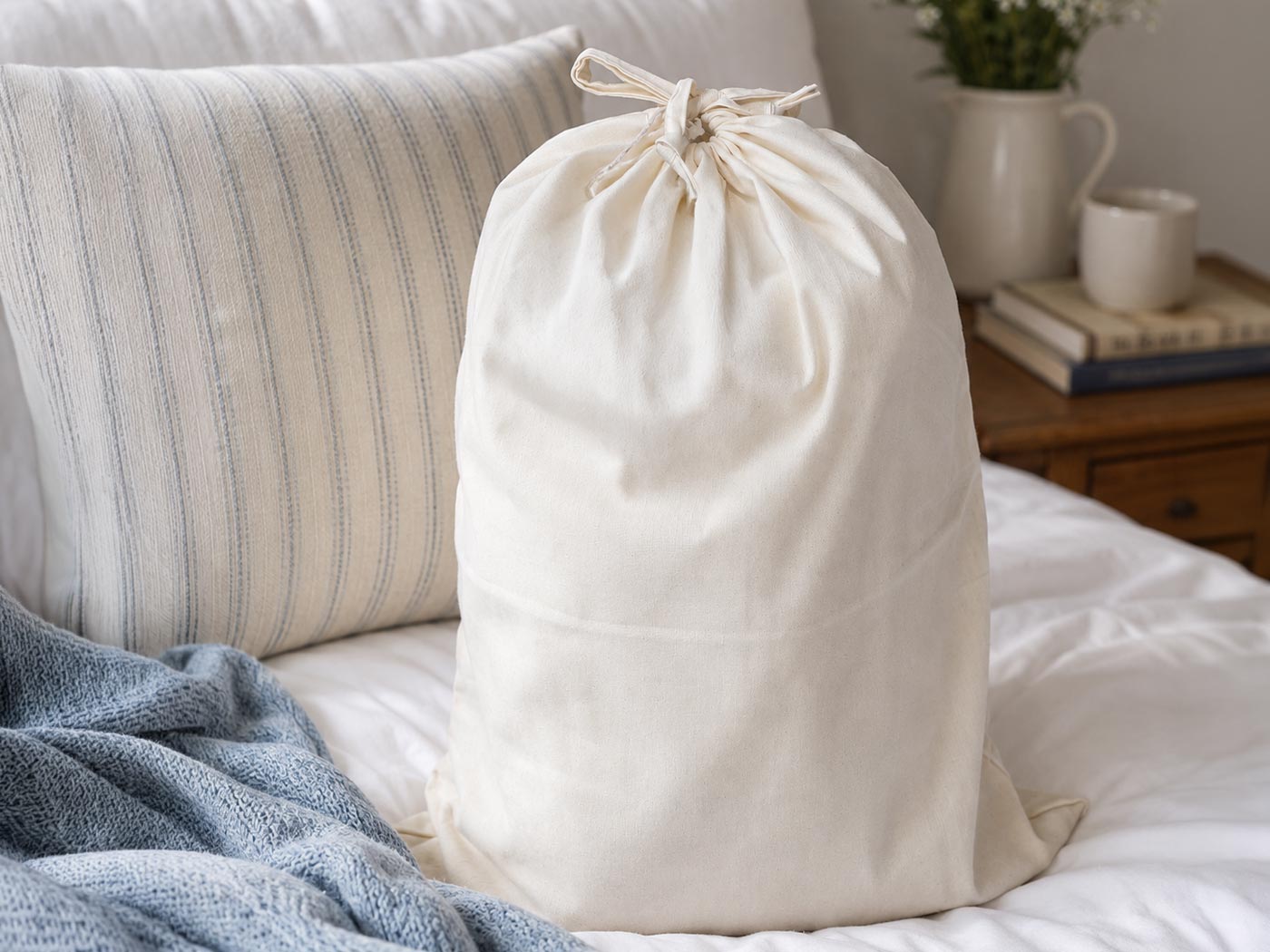 A folded cream duvet inside an open breathable cotton storage bag